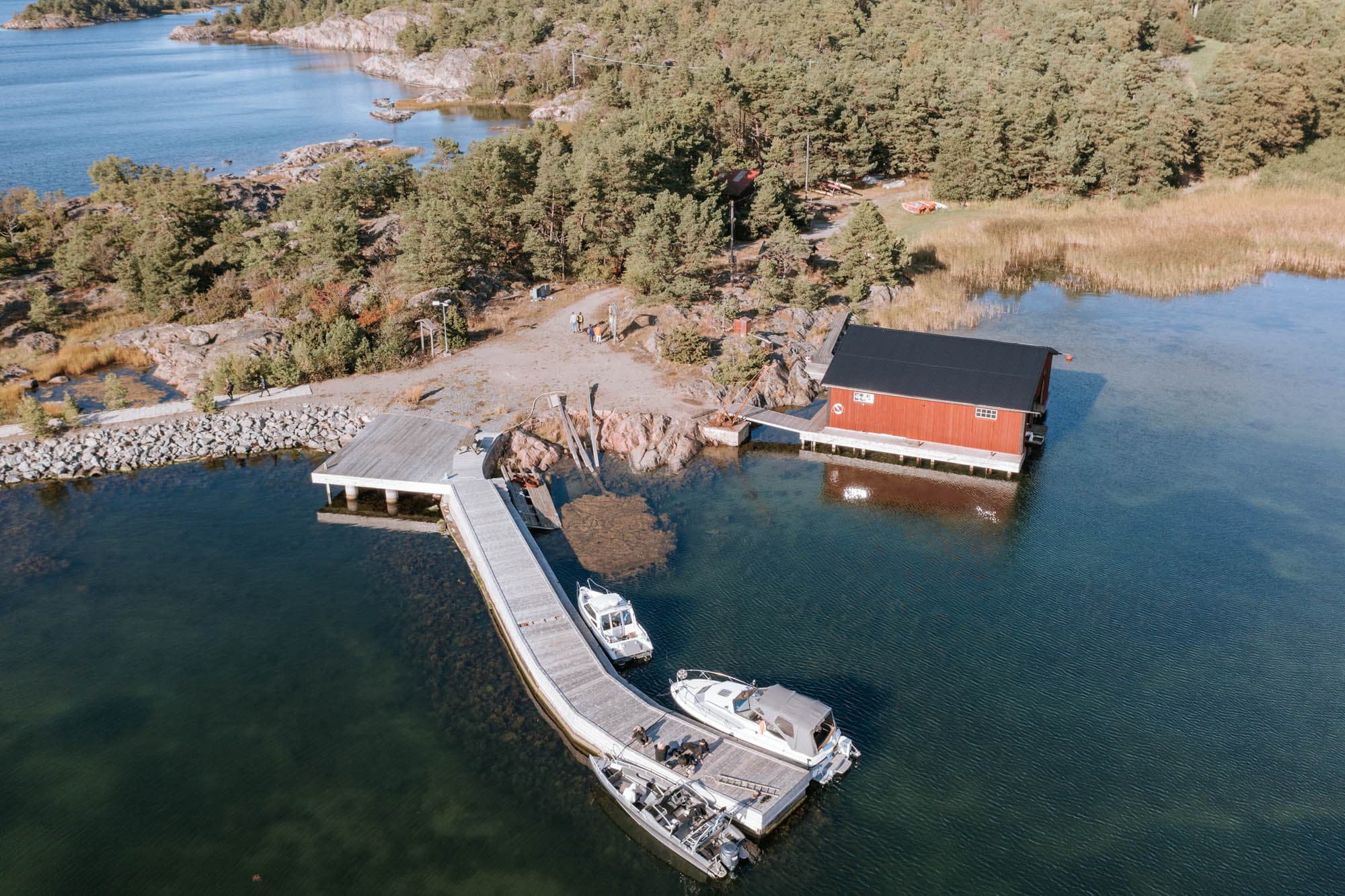 Fjärdlångs brygga och sjöbod sedda ovanifrån, med båtar förtöjda vid bryggan